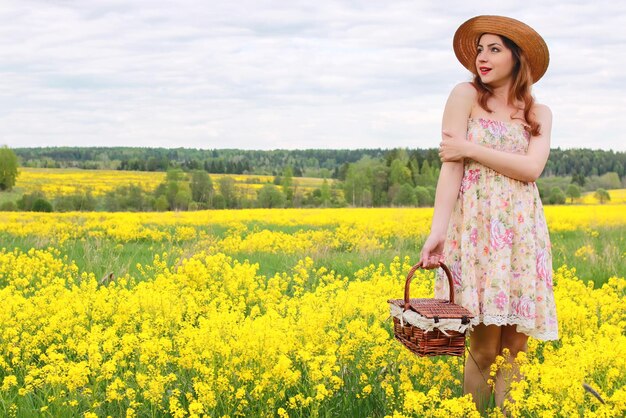 Menina em um campo de flores com uma cesta e um chapéu