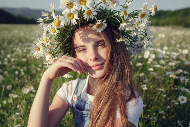 Menina em um campo de flores margarida. meninas em uma coroa de margaridas brancas, o conceito e a ideia de uma infância feliz