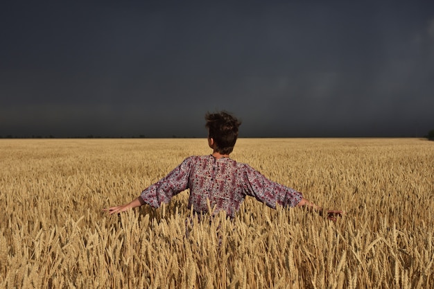 Menina em um campo de trigo antes de uma tempestade