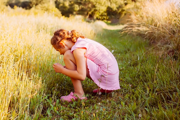 Menina em um campo de verão em um dia quente e ensolarado