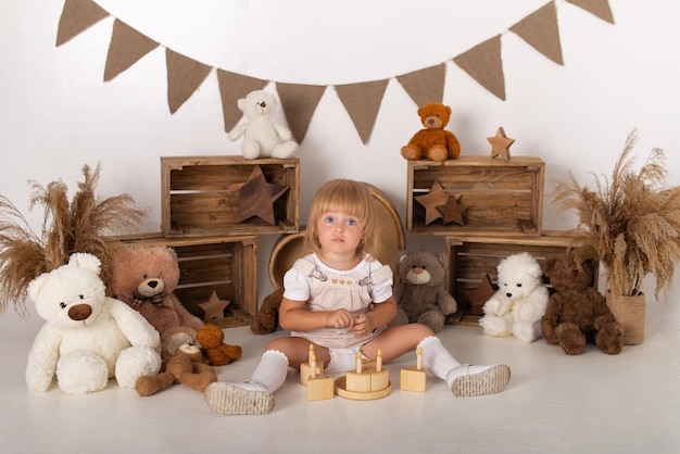 Menina em um fundo branco com um bolo e ursinhos de pelúcia.