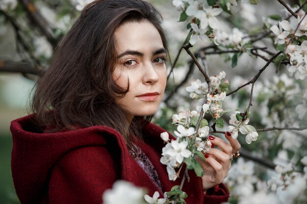 Menina em um jardim florido com um casaco marrom