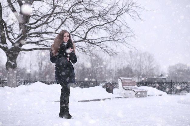 Menina em um parque de inverno à tarde na neve