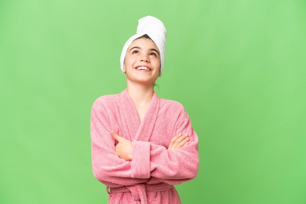 Menina em um roupão de banho sobre fundo croma chave isolado olhando para cima enquanto sorria