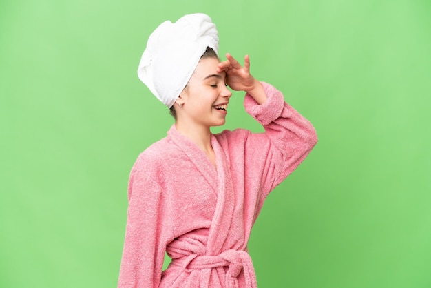 Menina em um roupão de banho sobre fundo croma isolado percebeu algo e pretendendo a solução