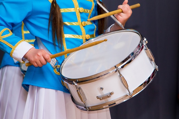 Menina em um terno elegante tocando bateria durante evento solene