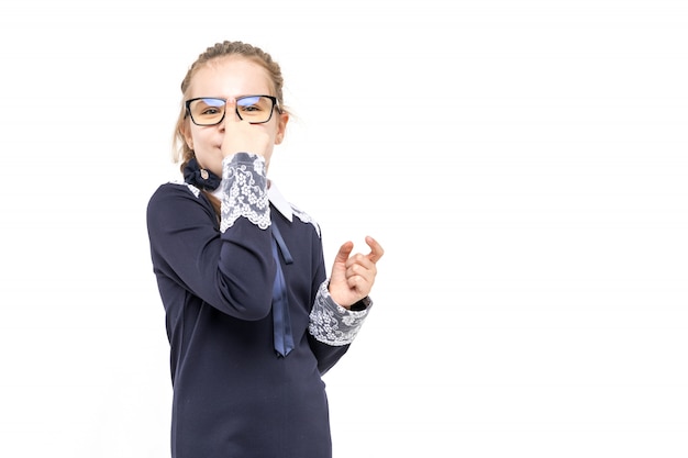 Foto menina em um uniforme azul da escola emocionalmente posando em um fundo branco