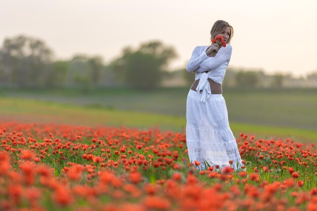 Menina em um vestido branco no campo de papoulas