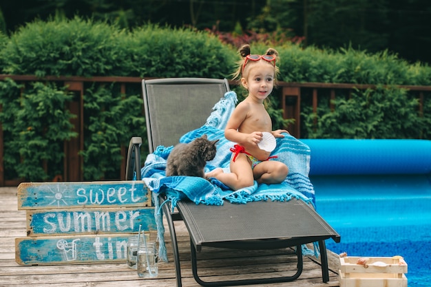 menina em uma cadeira junto à piscina