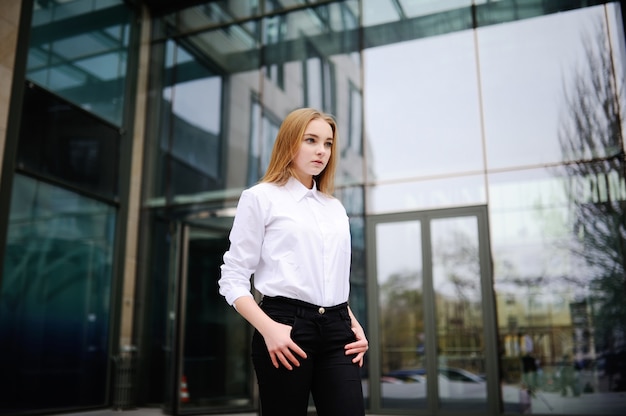 Menina em uma camisa branca no fundo do edifício de vidro