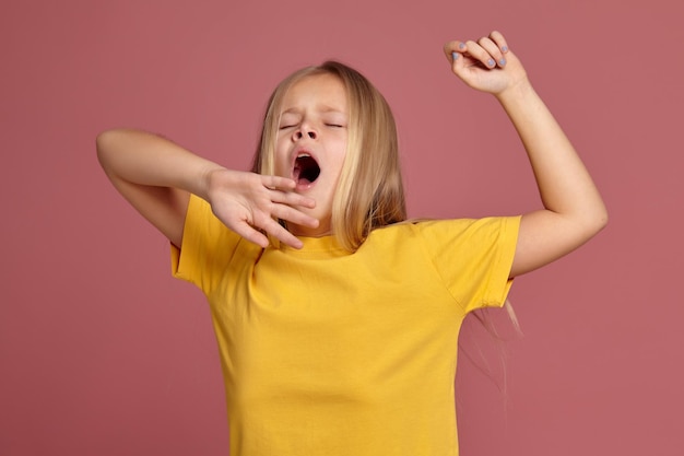 Menina em uma camiseta amarela. alongamentos e bocejos