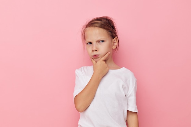 Menina em uma camiseta branca sorri fundo rosa