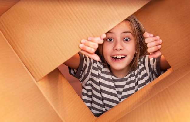 menina em uma camiseta listrada abre uma caixa de papelão