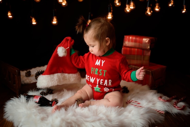 Menina em uma fantasia de natal vermelha com guirlandas retrô senta-se em uma pele