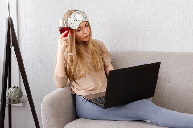 Menina emocional descontente com uma taça de vinho olhando para o laptop