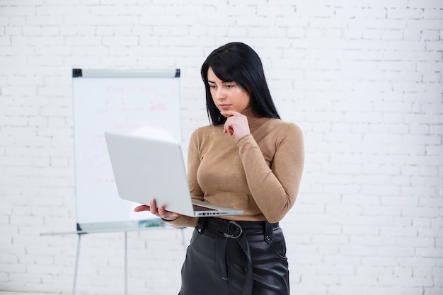 Menina empresária, professora, treinadora ensina e fala sobre um novo projeto em pé perto do quadro-negro