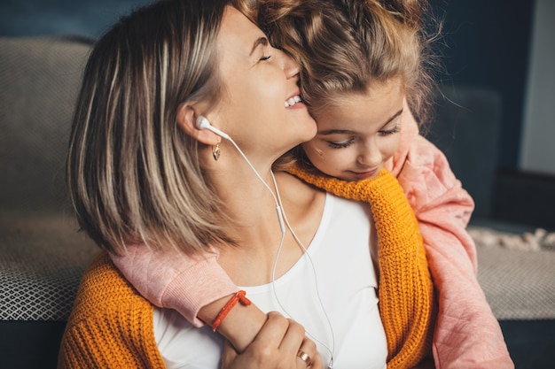 Menina encantadora abraçando a mãe enquanto ela ouve música no chão