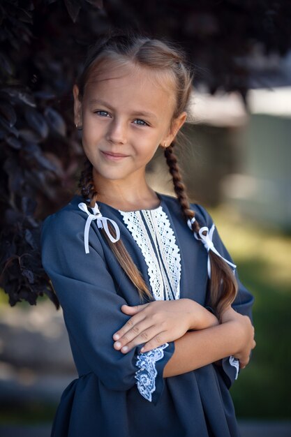 Menina encantadora com um vestido retrô, andando na cidade em um dia ensolarado de verão. Menina usa uniforme escolar.