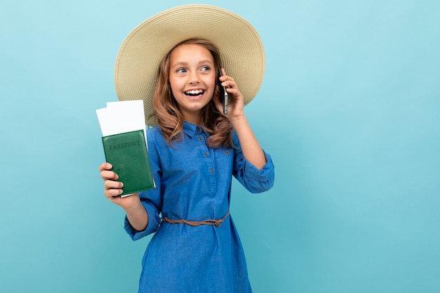 Menina encantadora mostra um passaporte com bilhetes, fala ao telefone e se alegra