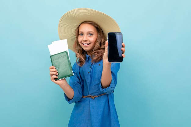 Menina encantadora mostra um passaporte com bilhetes, telefone e se alegra