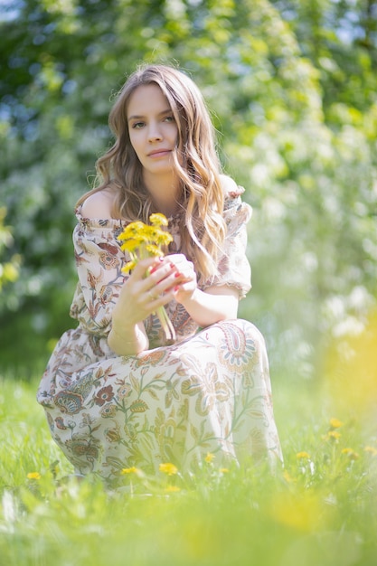 menina encantadora sentou-se coletando flores