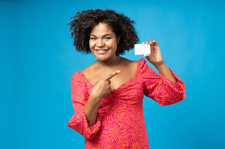Foto menina encaracolada sorridente com cartão na mão sobre fundo azul