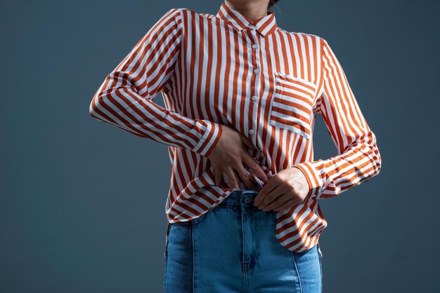 Foto menina enfiando uma camisa listrada em jeans