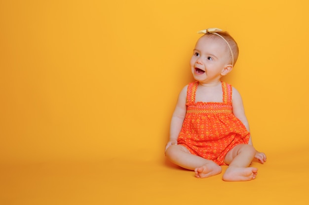 Menina engatinhando em um fundo amarelo segurando uma flor