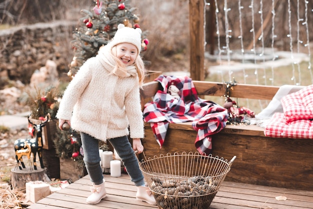 Menina engraçada brincando com enfeites de Natal ao ar livre