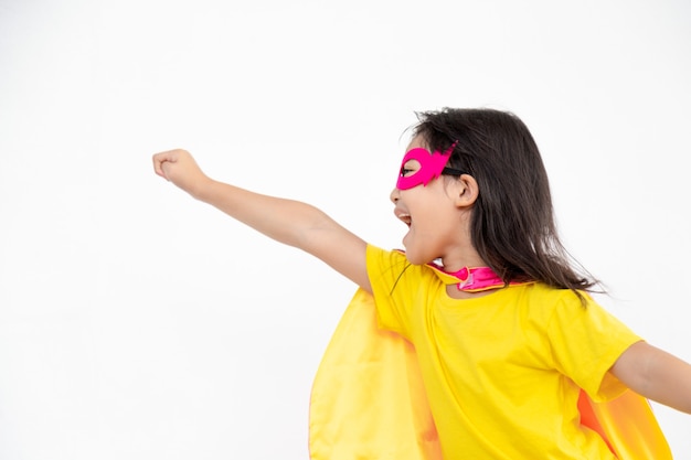 Menina engraçada jogando super-herói de poder sobre fundo branco. Conceito de super-herói.