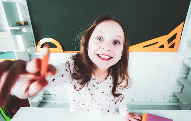 Menina engraçada na sala de aula perto da mesa do quadro-negro a criança está aprendendo na classe educação pré-escolar