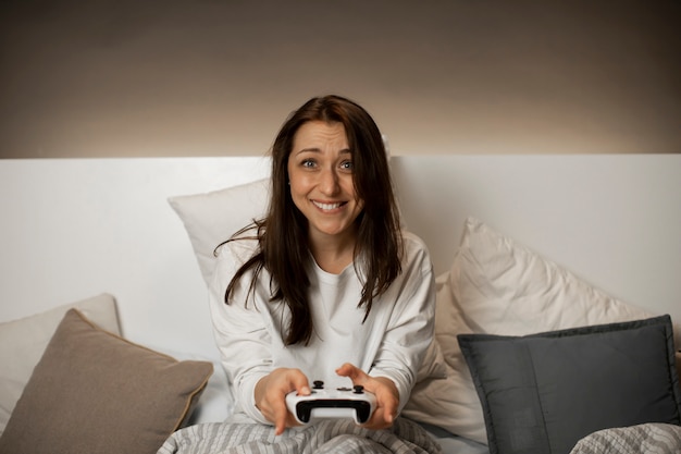 Menina engraçada sorridente joga videogame no console com emoção antes de dormir