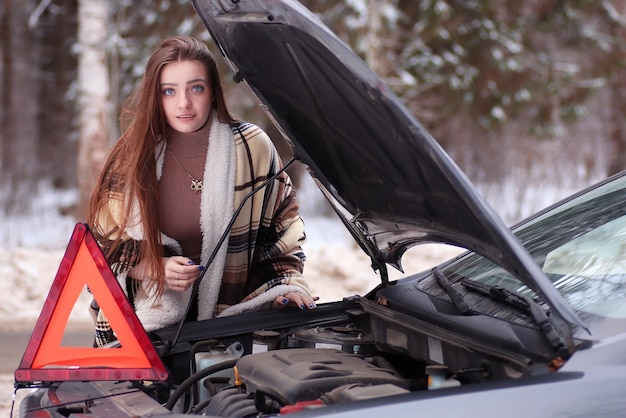Menina enrolada em um cobertor colocado perto do carro quebrado esperando por ajuda