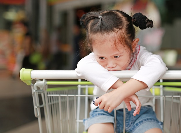 Menina entediada asiática criança sentada no carrinho