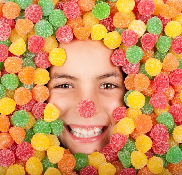 Foto menina enterrada em jujubas coloridas