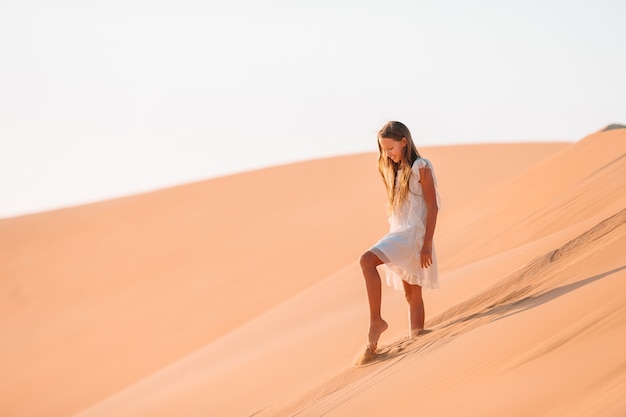 Menina entre dunas no deserto nos Emirados Árabes Unidos