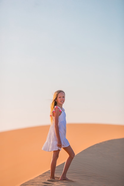 Menina entre dunas no deserto nos emirados árabes unidos