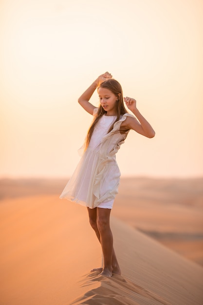 Menina entre dunas no deserto nos Emirados Árabes Unidos