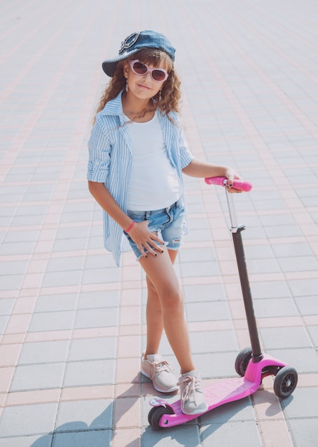 Menina equitação scooter ao ar livre.