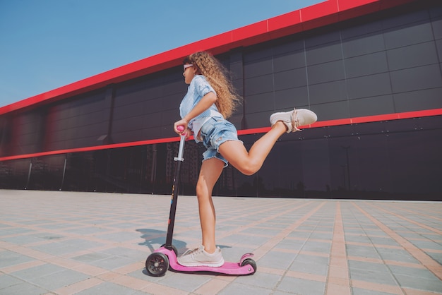 Menina equitação scooter ao ar livre.