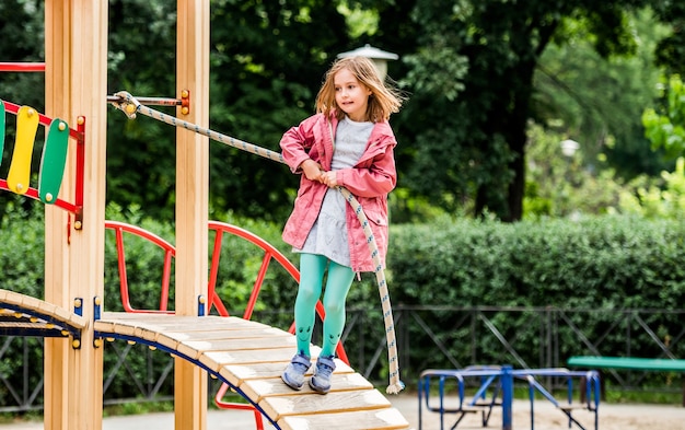 Menina escalando corda no parquinho infantil no parque