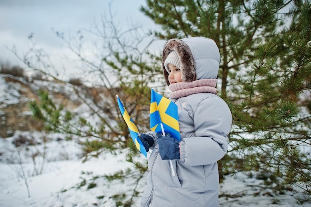 Menina escandinava com bandeira da Suécia na paisagem sueca de inverno