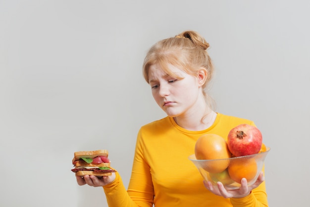 Foto menina escolhe entre alimentos saudáveis e insalubres