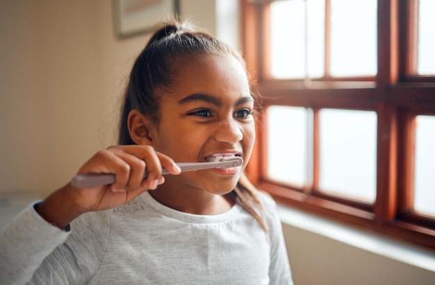 Menina escovando dentes escova de dentes para higiene e boca limpa hálito fresco para cuidados bucais e saúde bucal Criança negra limpando com pasta de dente no banheiro bem-estar em casa de família e gengivas saudáveis