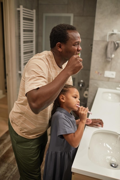 Menina escovando os dentes com o pai