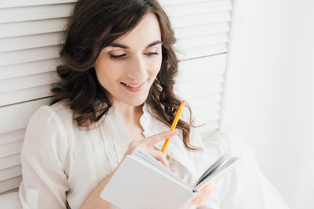 Menina escreve em um caderno na cama