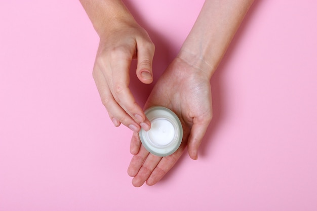 Menina esfregando as mãos em creme cosmético para a pele