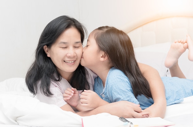 menina está beijando sua bela jovem mãe na bochecha