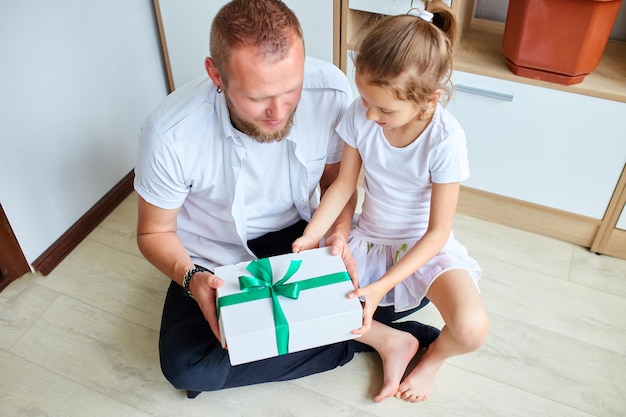 Menina está dando a seu pai bonito uma caixa de presente no dia dos pais