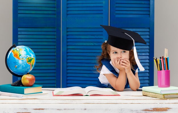 Menina está estudando enquanto usava um chapéu de formatura